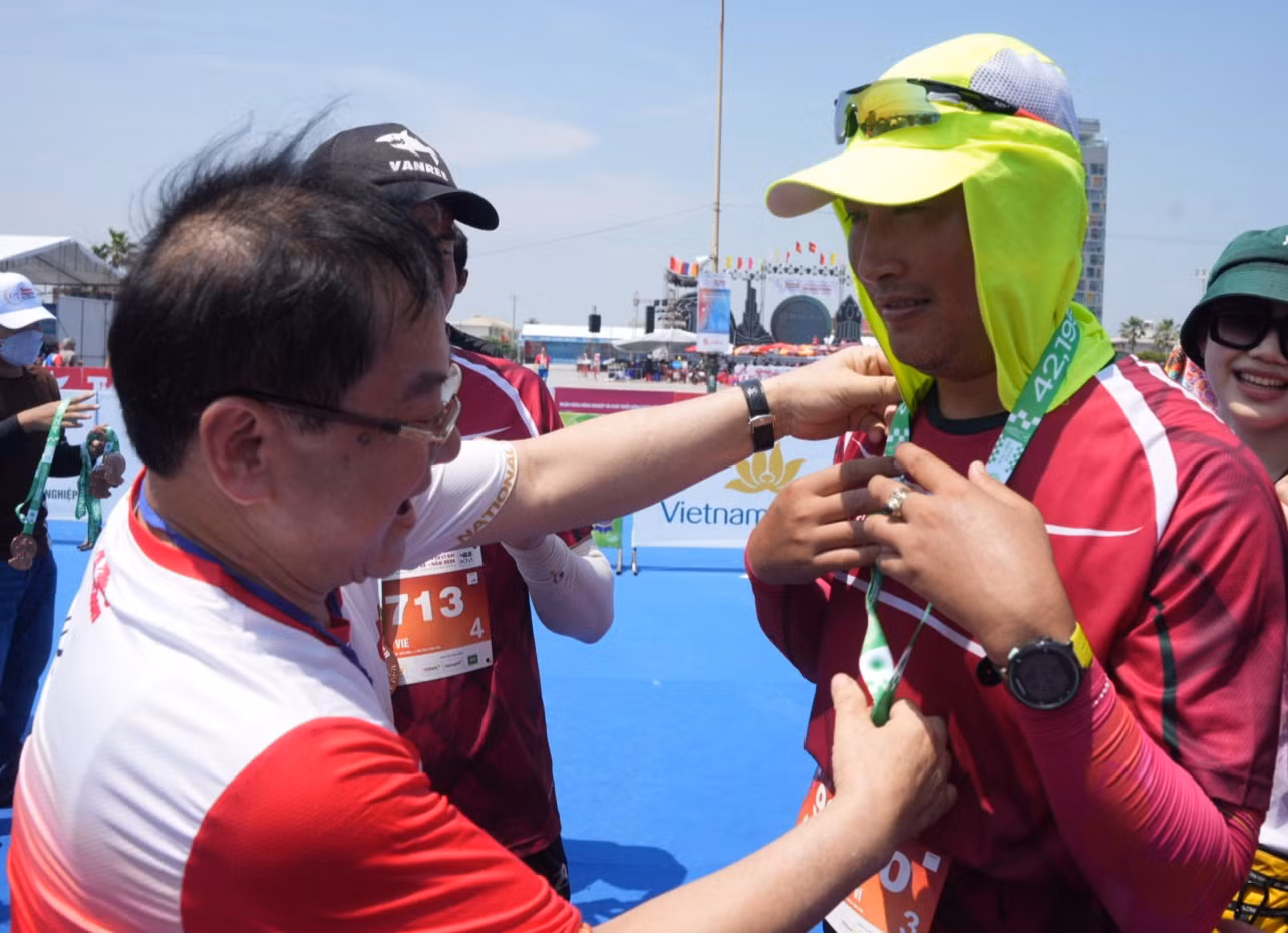 Nhà báo Lê Xuân Sơn - Tổng Biên tập báo Tiền Phong, đồng Trưởng Ban tổ chức Tiền Phong Marathon 2024, trao huy chương tặng vận động viên ở vạch đích.