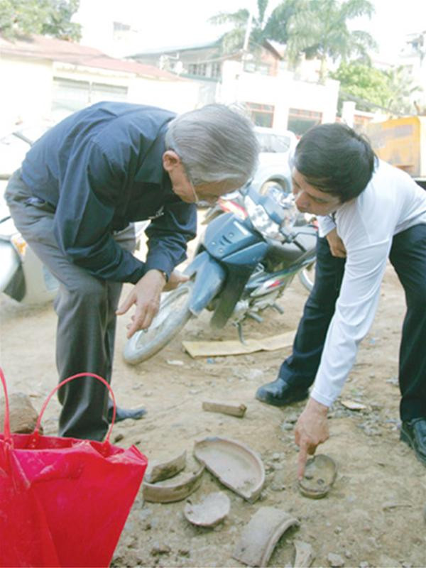 GS Phan Huy Lê (trái) và GS-TS Tống Trung Tín xem các mảnh hiện vật trên đoạn thành cổ vừa bị phá. Ảnh: Khánh Linh