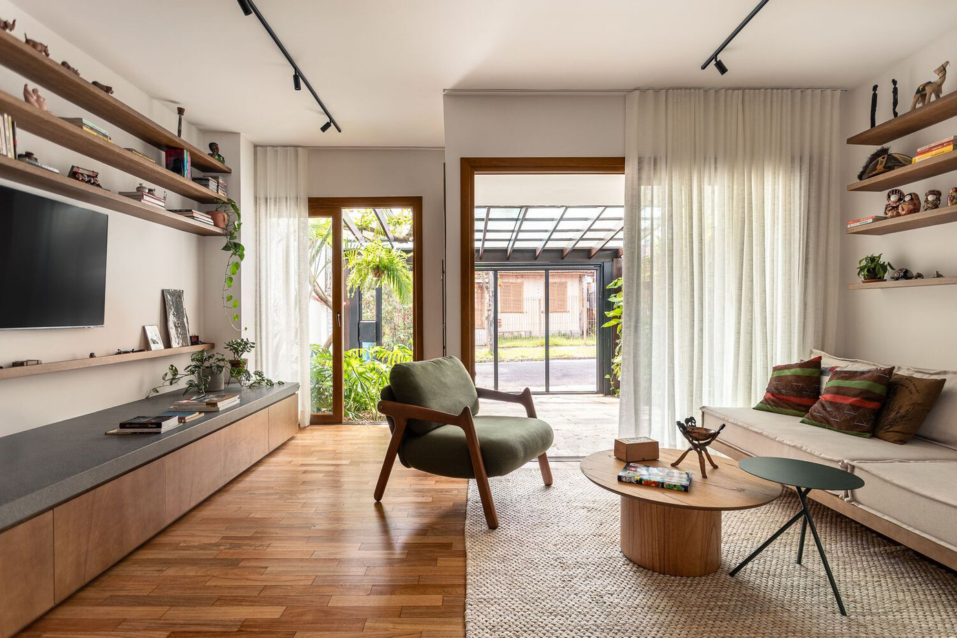 Dọc theo một bên tường trong phòng khách là hệ tủ liên hoàn, chi tiết về cả công năng lẫn thẩm mỹ. Đây vừa là kệ tivi, ghế ngồi tích hợp, vừa kéo dài thành bàn bếp, tủ chứa đồ liền mạch từ phòng khách sang bếp. Đặc biệt, một lò sưởi nhỏ được đặt tích hợp khéo léo trở thành điểm nhấn ấm cũng giữa không gian hiện đại.