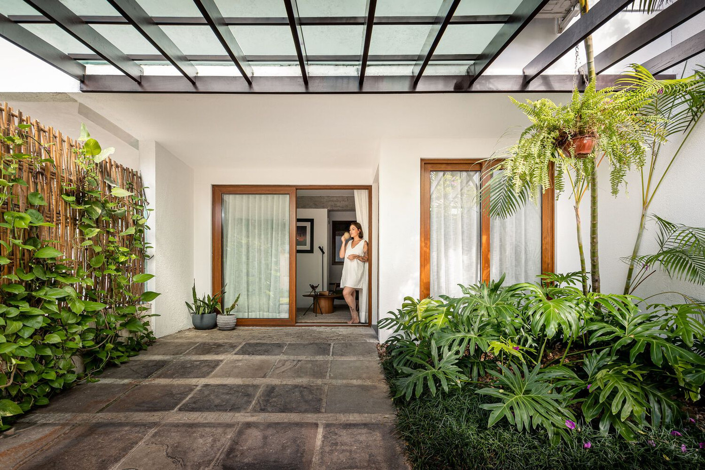 Trước khi cải tạo, tầng trệt của ngôi nhà khá rời rạc với sàn lát gạch sứ xám lạnh, phòng khách tối và bị ngăn cách bởi một ô cửa nhỏ giữa phòng khách và phòng bếp. Bây giờ mặt tiền được mở rộng hoàn toàn bằng hệ cửa kính lớn để đón gió và đón sáng vào không gian phòng khách.