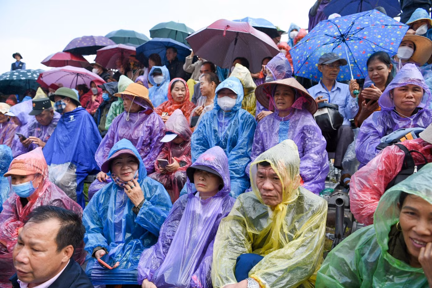 Người dân "cuộn mình" trong chiếc áo mưa mỏng để thưởng thức chương trình lễ hội lớn nhất trong năm tại đây.