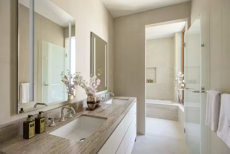 Phòng tắm riêng biệt gồm 5 thiết bị vệ sinh, sử dụng đá cẩm thạch Calacatta Vagli ốp toàn bộ tường và sàn, tích hợp dưới sàn sưởi nhiệt và bồn ngâm được bao bọc bởi lớp đá marble sang trọng. Các phòng tắm phụ sử dụng đá sứ châu Âu cho tường và sàn, kèm tủ thuốc thiết kế riêng với đèn tích hợp và ngăn kệ, mặt bàn đá Didimon Light kiểu thác đổ đầy nghệ thuật.