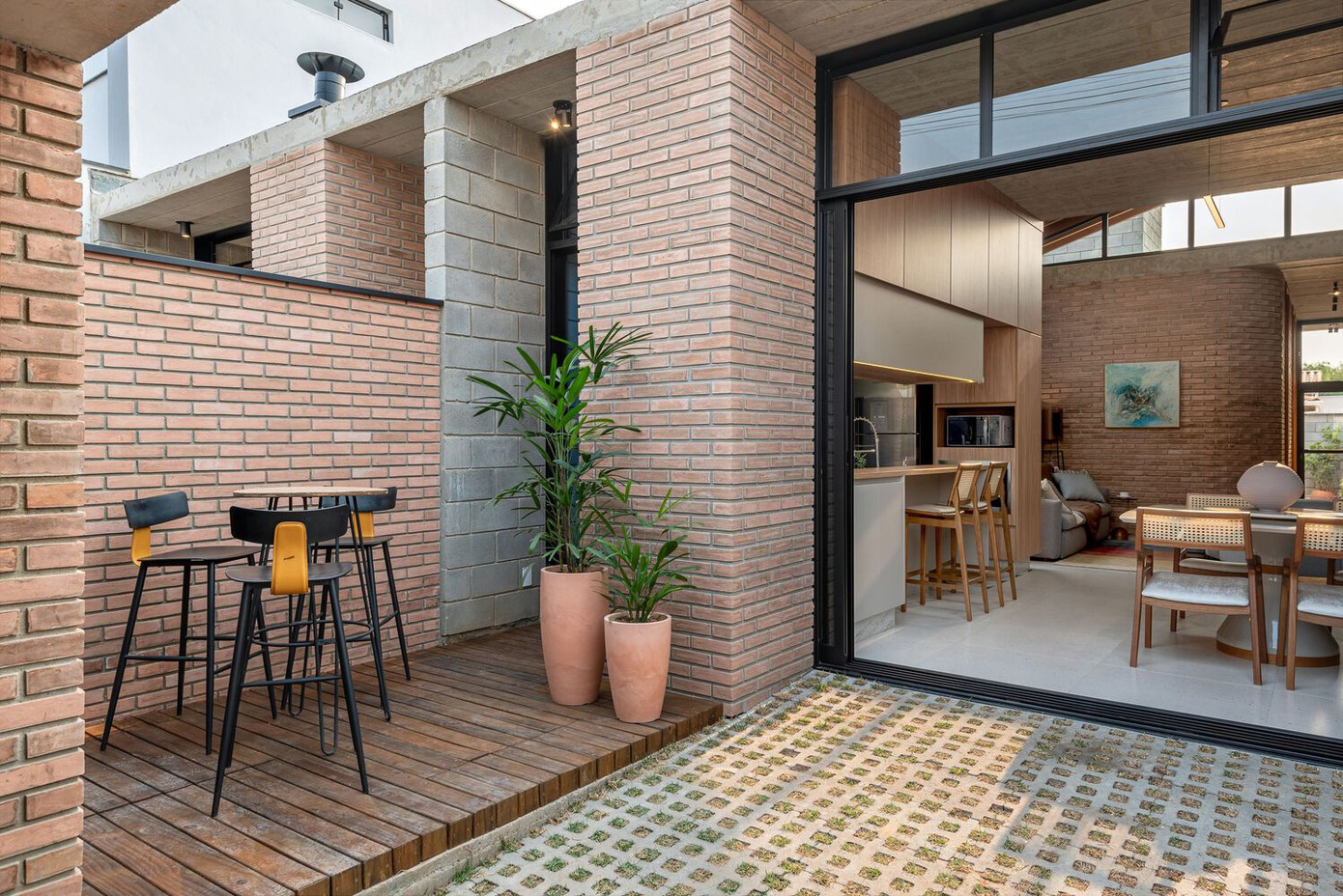 Thay vì bố trí hai chỗ đậu xe, ngôi nhà chỉ dành một vị trí để đỗ ô tô, phần còn lại được tận dụng làm sàn gỗ ngoài trời, tích hợp khu vực nướng BBQ - nơi gắn kết gia đình và bạn bè trong những buổi tụ họp.