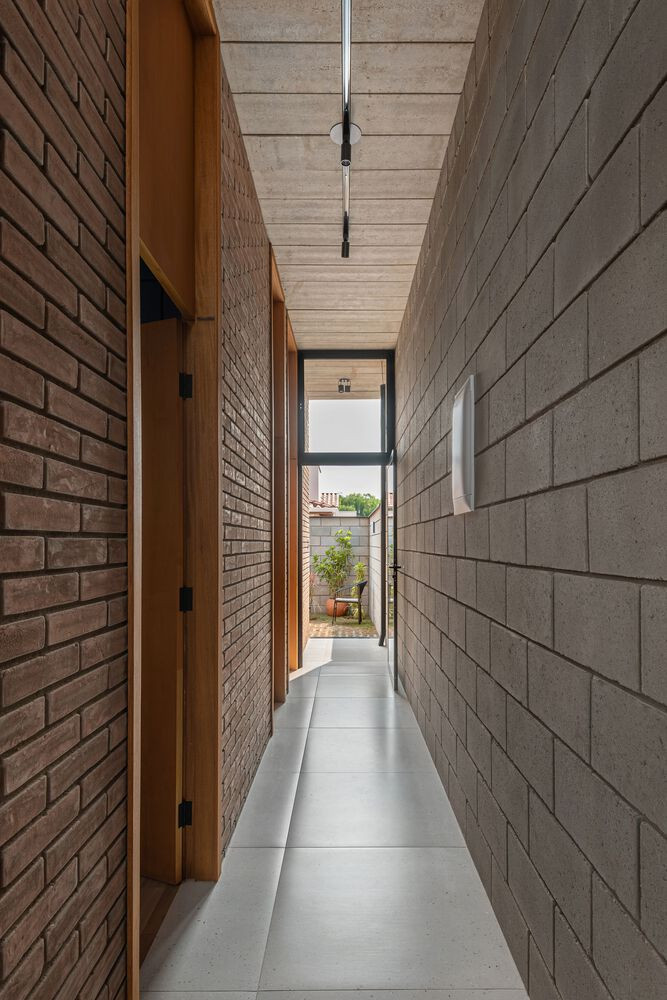 Hành lang liền mạch với cửa thông gió ra sân để đảm bảo không khí trong ngôi nhà luôn được lưu thông. Sân sau của ngôi nhà được thiết kế đa năng với một bên là khu vực giặt có mái che, một bên còn lại là khoảng sân trống để phơi đồ và thảm cỏ xanh.