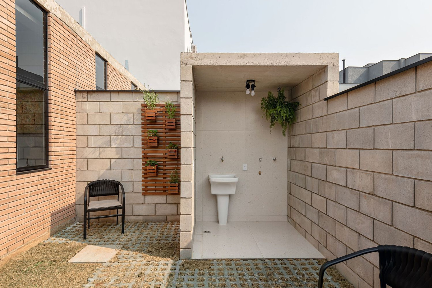 Thay vì bố trí hai chỗ đậu xe, ngôi nhà chỉ dành một vị trí để đỗ ô tô, phần còn lại được tận dụng làm sàn gỗ ngoài trời, tích hợp khu vực nướng BBQ - nơi gắn kết gia đình và bạn bè trong những buổi tụ họp.