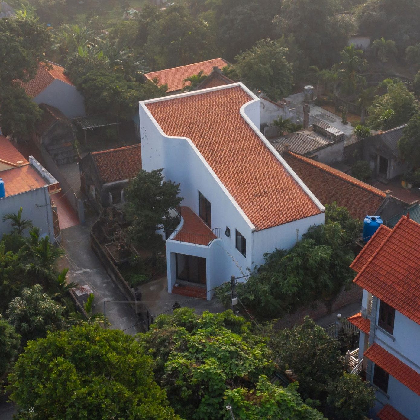 Lựa chọn loại ngói kiểu cũ và lợp theo cách truyền thống, ngôi nhà hai tầng mới xây như hoà mình vào vẻ cổ kính của nơi làng cổ. Việc thiết kế mái dốc một chiều về phía trước, vừa mang lại công năng cho vị trí két nước dưới mái phía sau, vừa tạo được tỷ lệ vừa phải với con ngõ nhỏ trước nhà.