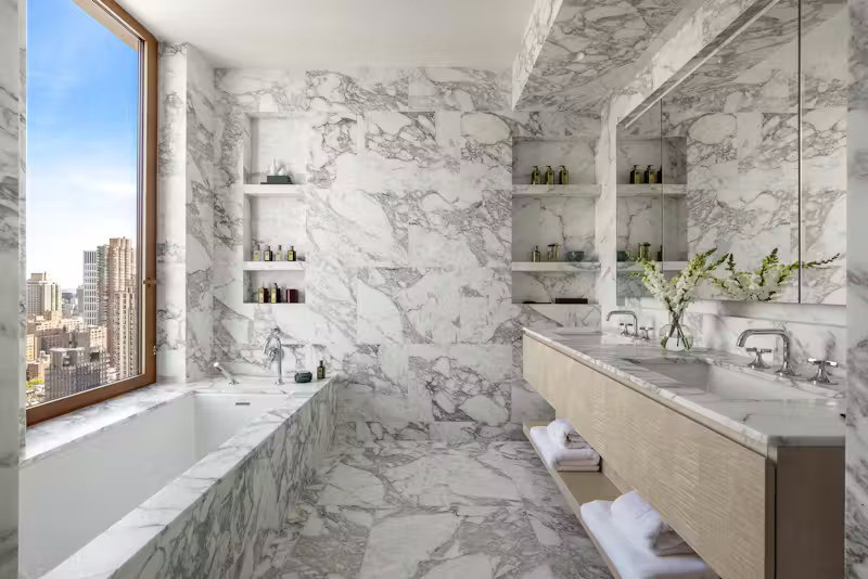 Phòng tắm riêng biệt gồm 5 thiết bị vệ sinh, sử dụng đá cẩm thạch Calacatta Vagli ốp toàn bộ tường và sàn, tích hợp dưới sàn sưởi nhiệt và bồn ngâm được bao bọc bởi lớp đá marble sang trọng. Các phòng tắm phụ sử dụng đá sứ châu Âu cho tường và sàn, kèm tủ thuốc thiết kế riêng với đèn tích hợp và ngăn kệ, mặt bàn đá Didimon Light kiểu thác đổ đầy nghệ thuật.