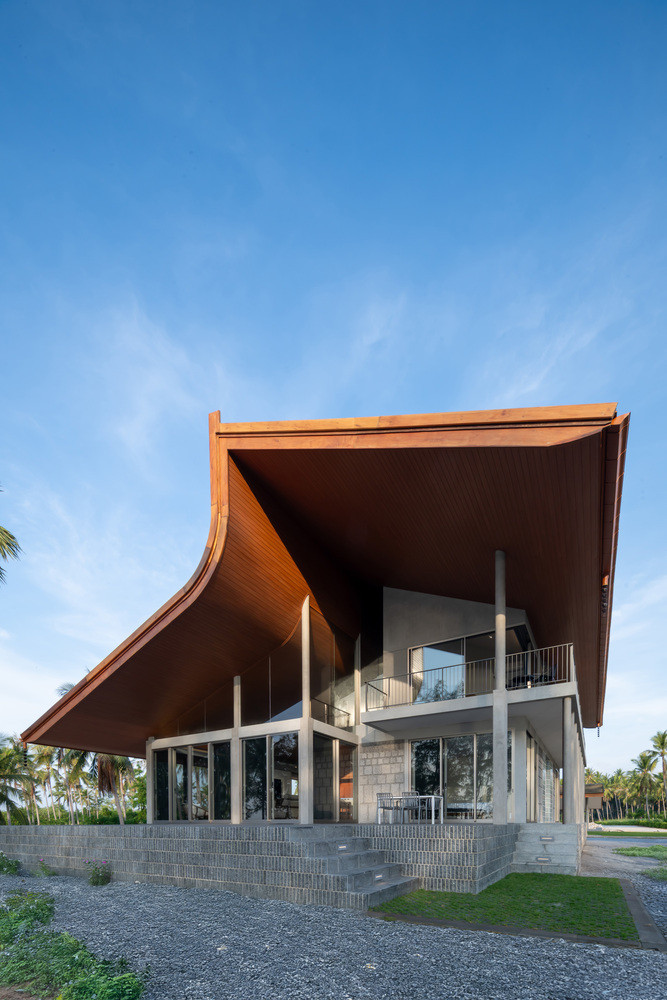 Ngôi nhà được xây dựng trên nền đá vững chắc, được che chở bởi một mái nhà lớn uốn lượn như làn sóng vỗ nhẹ giữa không trung.