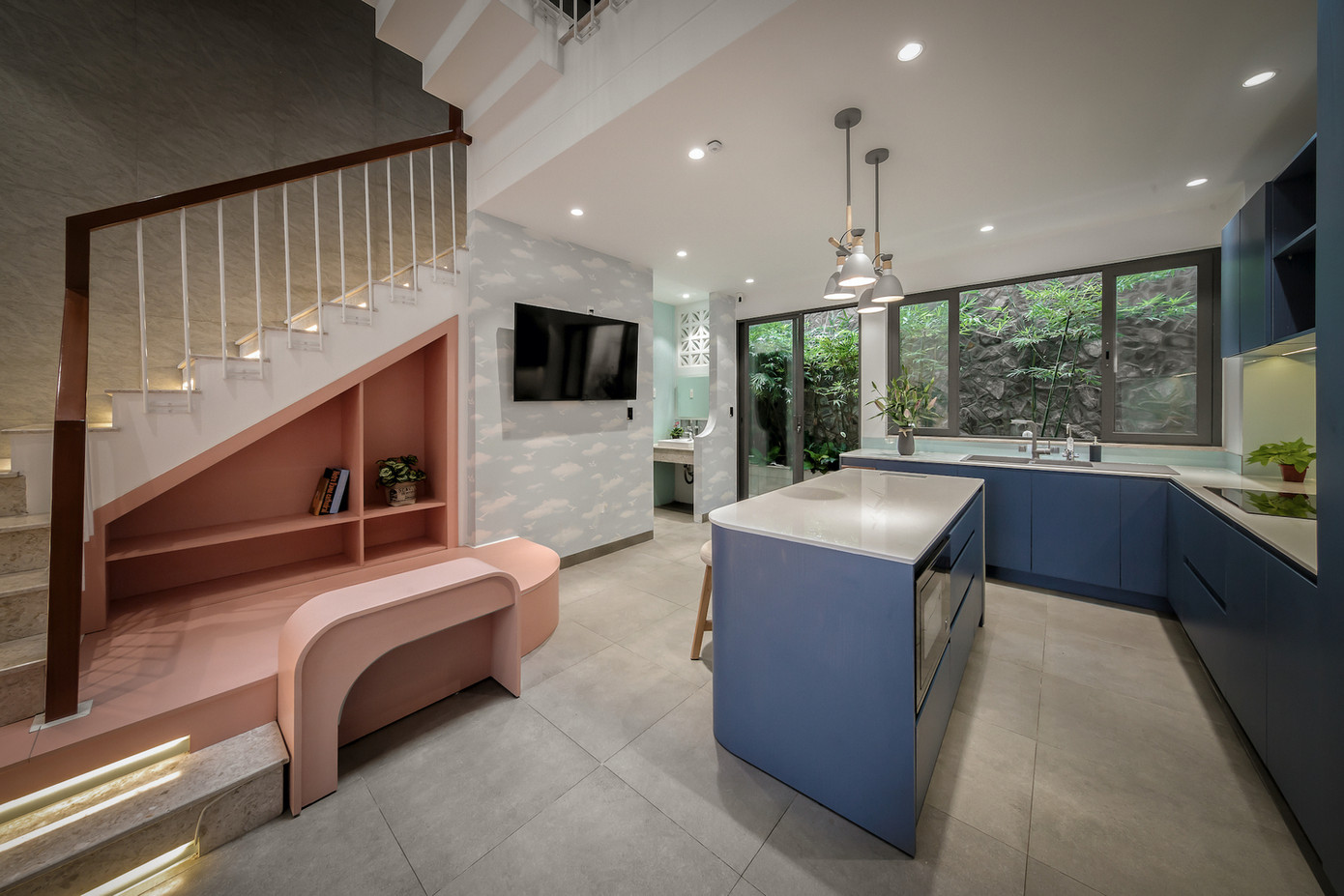 Tầng trệt là khu bếp và phòng ăn, nơi có thể nhìn thấy bầu trời qua giếng trời, mang lại cảm giác rộng mở và thư thái. Khu bếp được thiết kế liền kề sân sau, dù diện tích nhỏ nhưng vẫn đảm bảo sự tiện nghi, giúp người mẹ cảm thấy thoải mái khi nấu nướng.