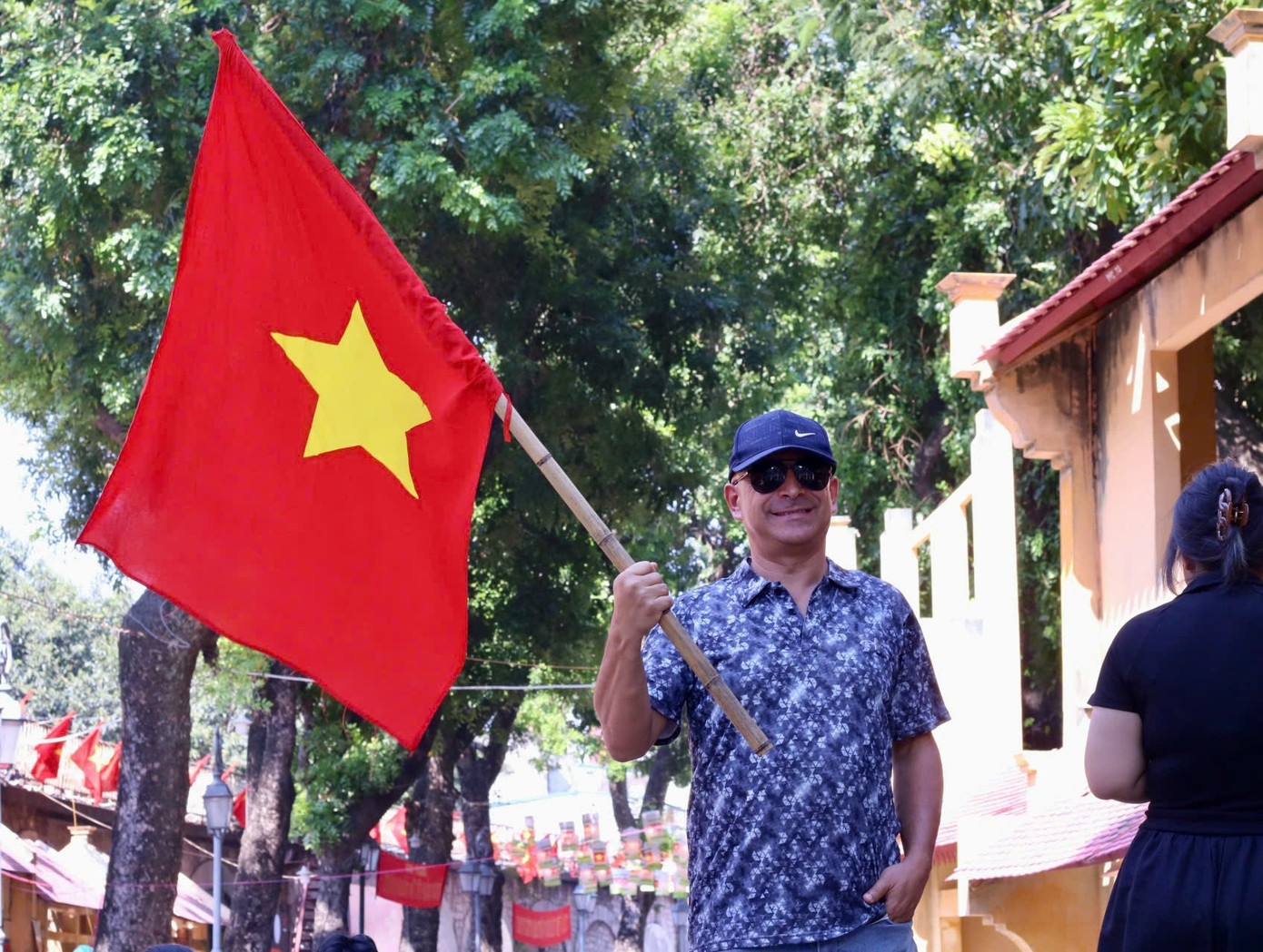 Du khách nước ngoài hào hứng chụp hình với cờ đỏ sao vàng tại không gian trưng bày.