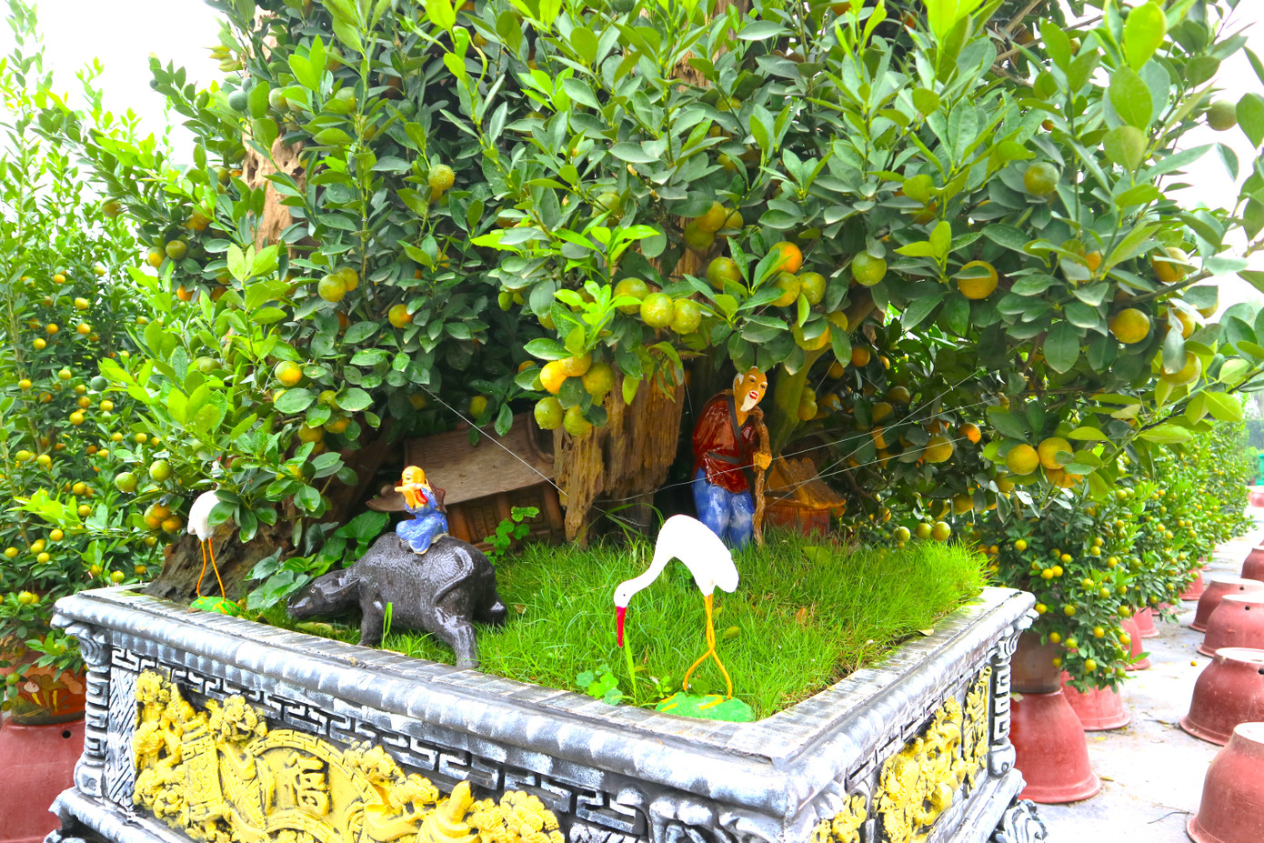 Để tạo thêm điểm nhấn cho những chậu quất cảnh, nhà vườn đã trang trí thêm những tiểu cảnh dưới gốc để giúp chậu cây thêm phần sống động.