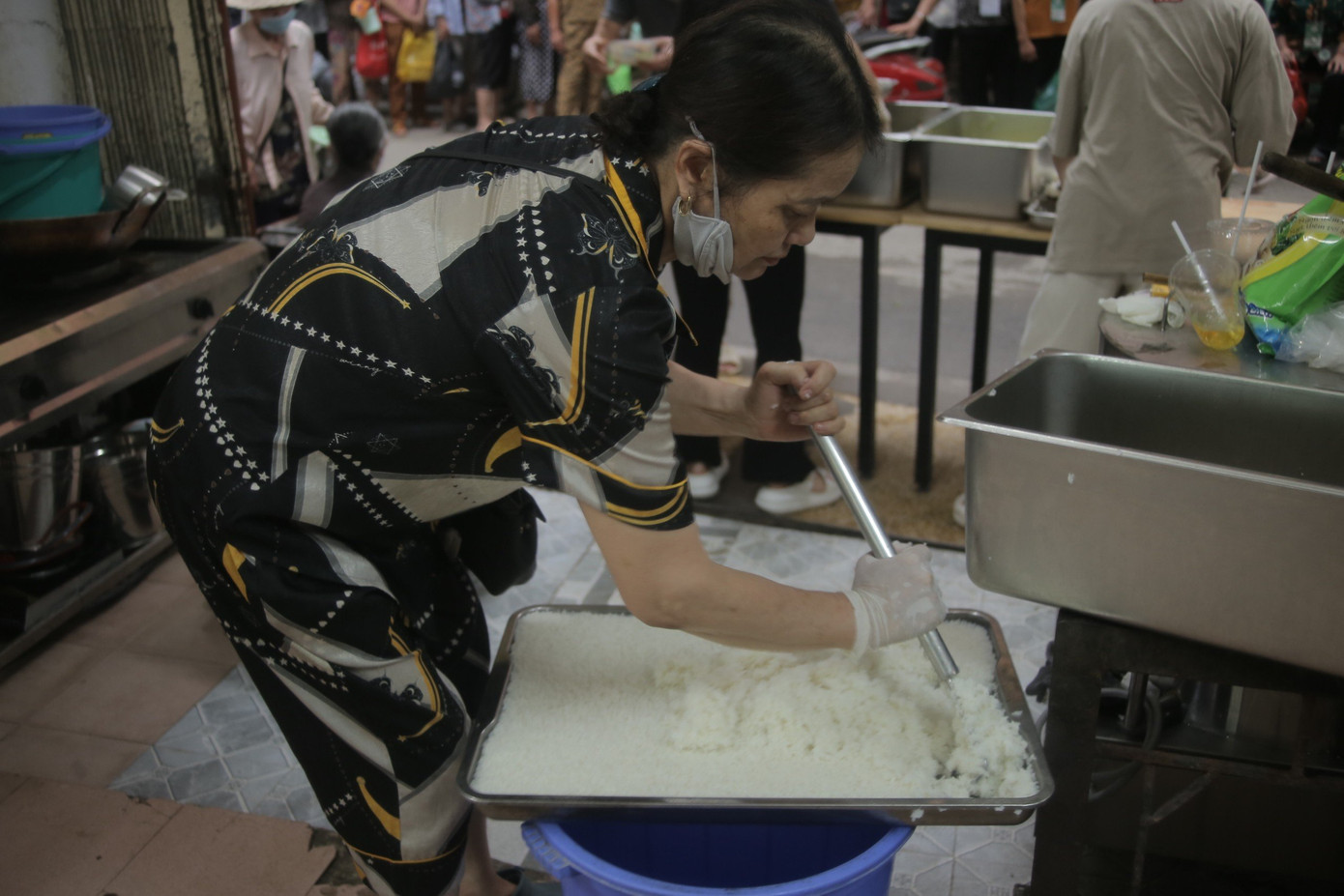 Mỗi ngày, cô Xoa nấu khoảng 12 khay cơm đầy để phát cho bà con.