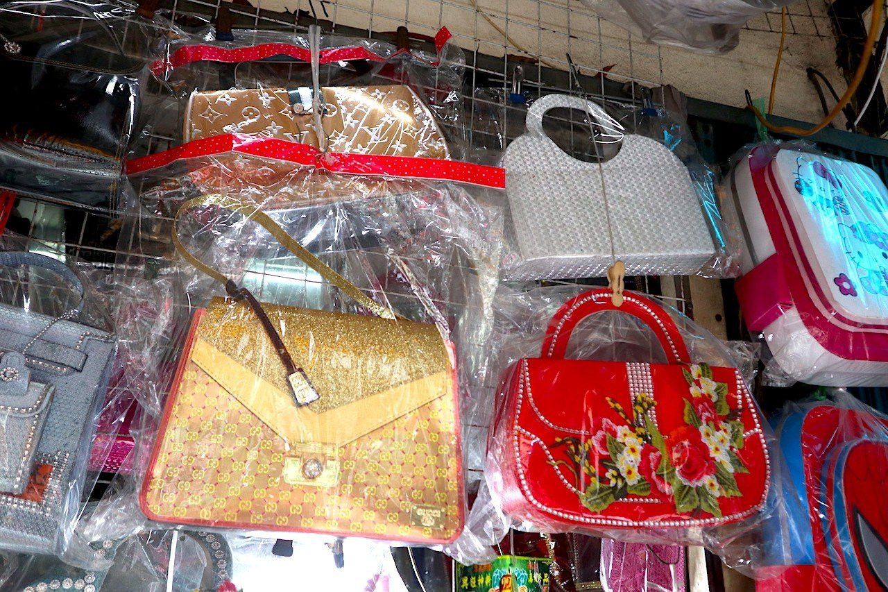 Nhiều mặt hàng được làm theo mẫu của các nhãn hiệu Gucci, Louis Vuitton,... treo đầy trên kệ hàng Nhiều mặt hàng được làm theo mẫu của các nhãn hiệu Gucci, Louis Vuitton,... treo đầy trên kệ hàng