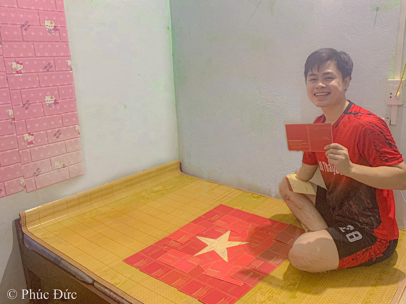 Nguyễn Phúc Đức bên lá cờ Tổ quốc được "vẽ" từ giấy chứng nhận hiến máu của mình.