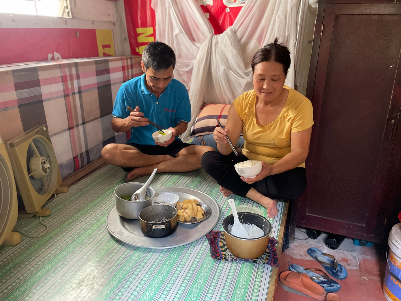 Phòng chỉ đủ diện tích kê chiếc giường đơn, chiếc tủ nhỏ và một vài vật dụng sinh hoạt khác. Chiếc giường "đa năng" của vợ chồng ông bà đảm nhận một lúc nhiều nhiệm vụ từ chỗ ngủ, nghỉ ngơi, bây giờ kiêm "nhiệm vụ" làm bàn ăn cho ông bà.