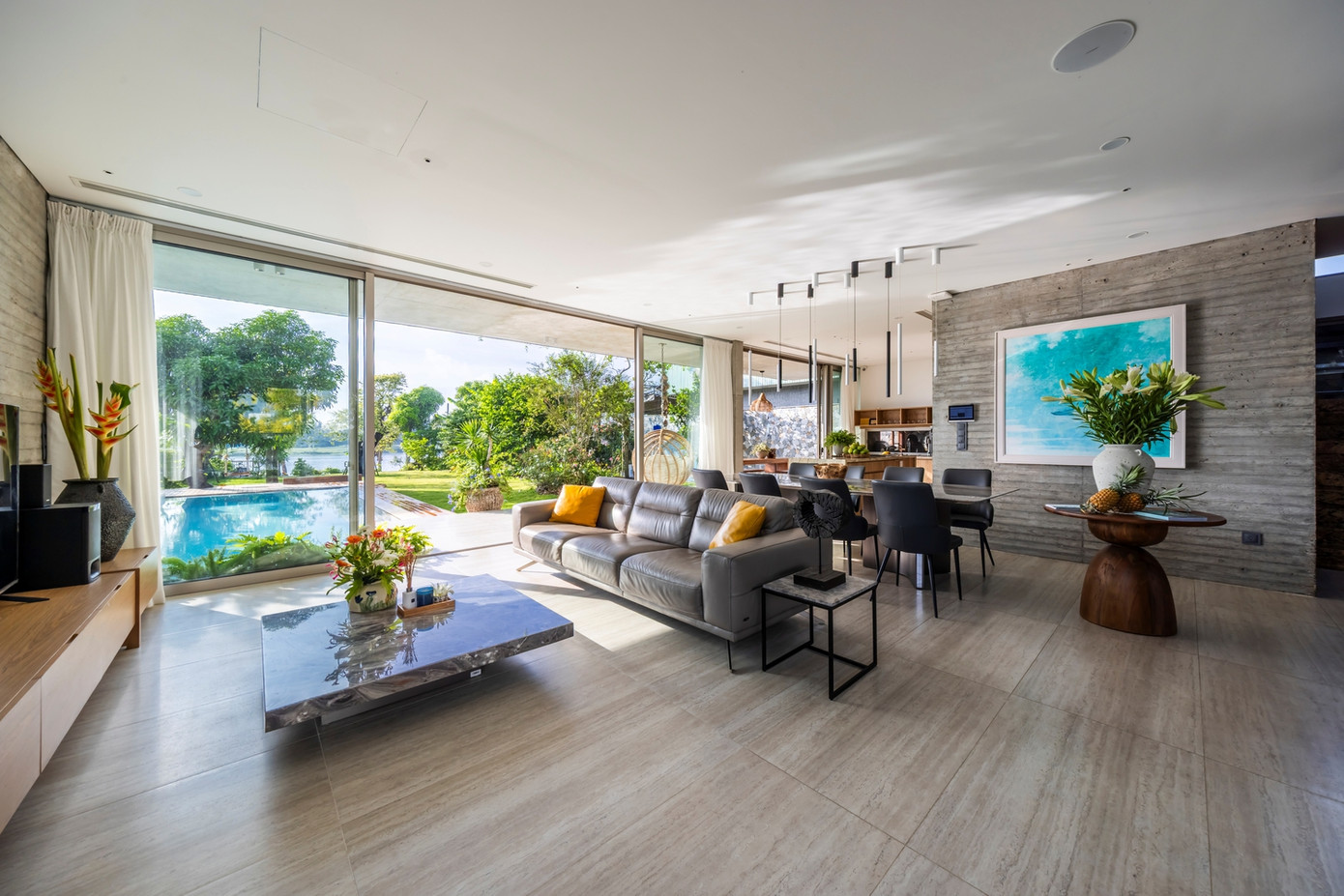 Không gian phòng khách nhìn ra bể bơi và được ngăn cách nhau bởi hệ cửa kính lớn sát trần nhằm tạo sự kết nối liền mạch giữa không gian trong và ngoài nhà.