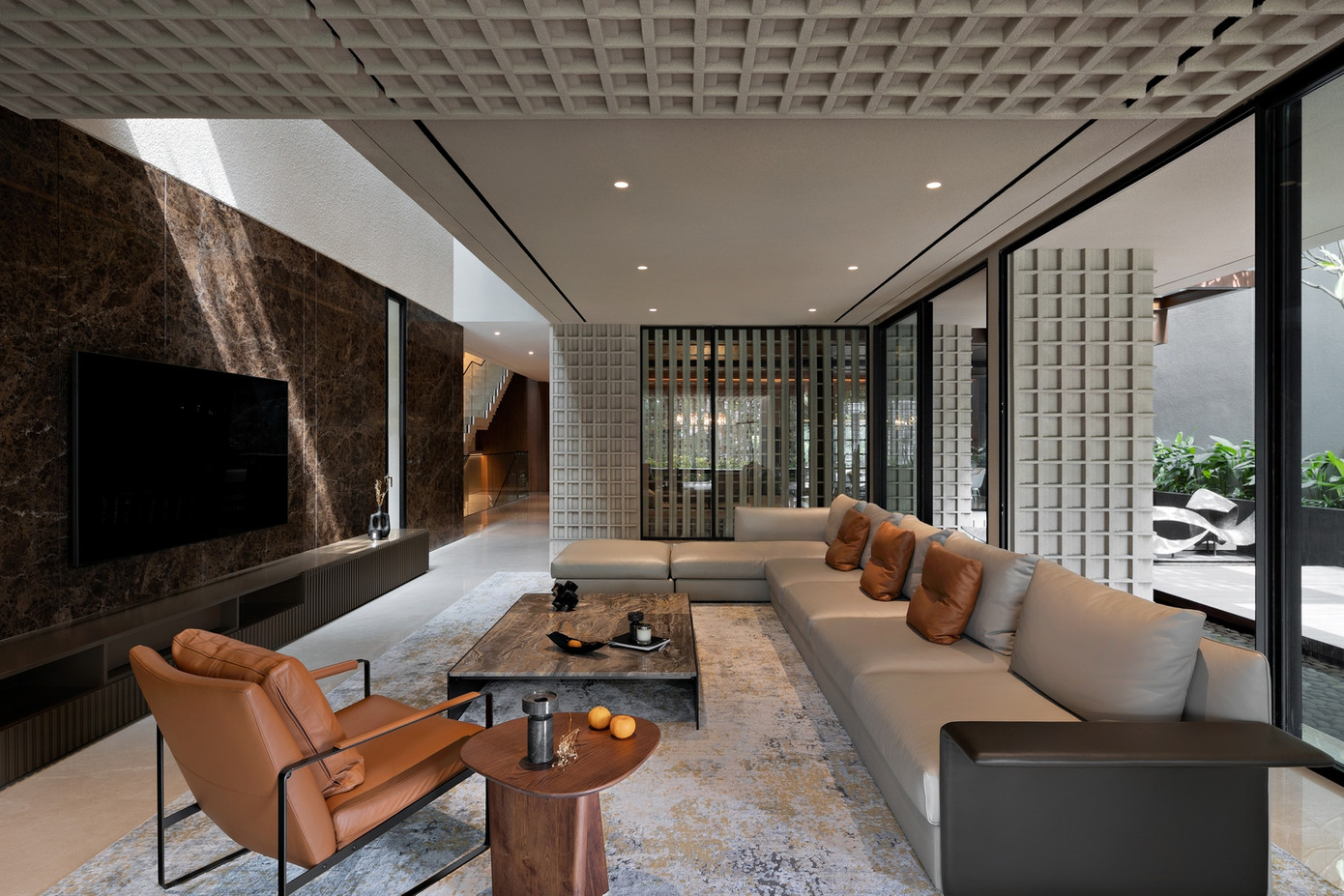 Phòng khách thoáng đãng, mở rộng qua các lớp cửa kính gần như xoá nhoà ranh giới trong - ngoài. Mặt đứng gạch thông gió còn kéo dài vào trần trong nhà.