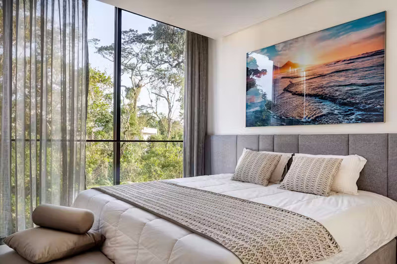 Điểm nhấn nổi bật tại phòng ngủ chính là ô cửa sổ lớn không có dầm ngang như một khung tranh hướng tầm nhìn ra cảnh quan tự nhiên ở cuối khu đất.