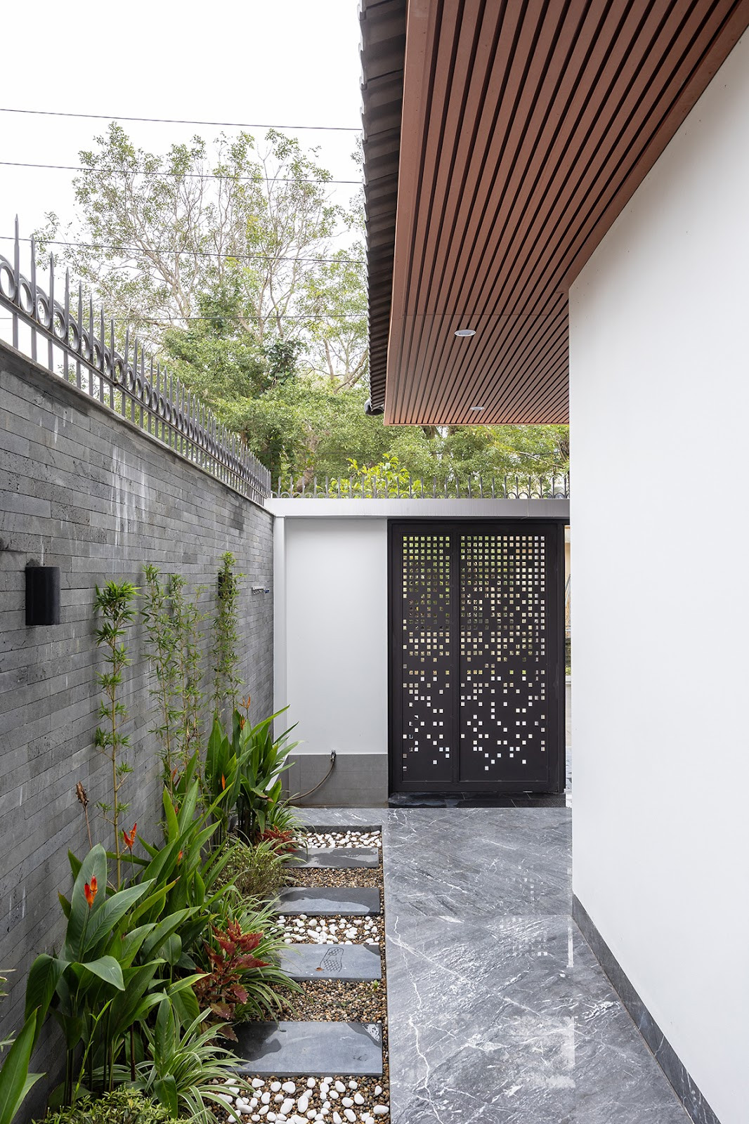 Ngôi nhà có hướng chính Nam, kiến trúc sư đã kết hợp khoảng hiên và vườn bên hông hướng Đông Nam tạo ra một vùng đệm, một khoảng trống vừa đủ để đón gió mát mẻ vào mùa hè oi bức. Khoảng sân vườn phía sau tạo điều kiện cho luồng gió dễ dàng lưu thông tự nhiên, góp phần duy trì vi khí hậu dễ chịu trong nhà.