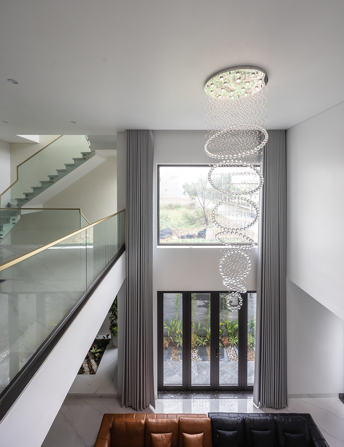 Một trong những điểm nhấn quan trọng của ngôi nhà là khoảng thông tầng trung tâm, kết nối trực tiếp các không gian trên lầu, bao gồm khu sinh hoạt chung của gia đình và hệ thống hành lang di chuyển. Không gian mở này không chỉ tăng cường sự tương tác giữa các thành viên mà còn giúp ngôi nhà thông thoáng, tràn ngập ánh sáng tự nhiên.