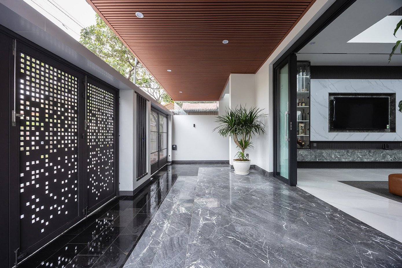 Từ cổng chính, khi mở hết cửa có thể nhìn xuyên suốt đến khoảng không gian bên ngoài mang lại cảm giác rộng rãi hơn so với diện tích thực. Khoảng đệm trước nhà giúp ngăn cách ngôi nhà với mặt đường khói bụi.