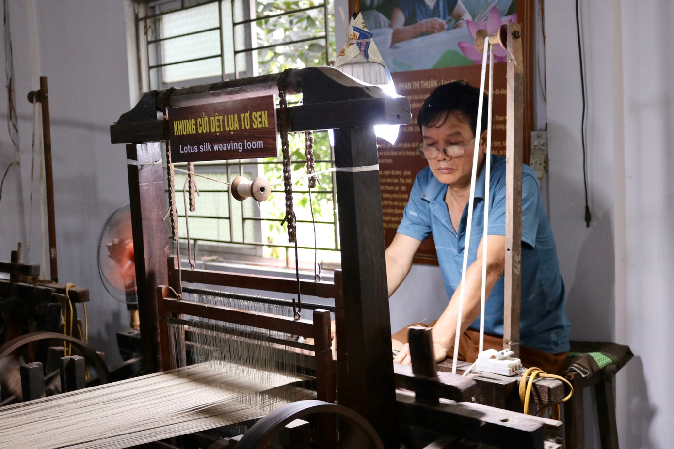 Máy dệt sợi tơ sen hoạt động cả ngày. Để có những tấm lụa với hoa văn đặc biệt, người đứng máy phải khéo léo tạo tác ngay khi đưa đẩy con thoi. Máy dệt sợi tơ sen hoạt động cả ngày. Để có những tấm lụa với hoa văn đặc biệt, người đứng máy phải khéo léo tạo tác ngay khi đưa đẩy con thoi.