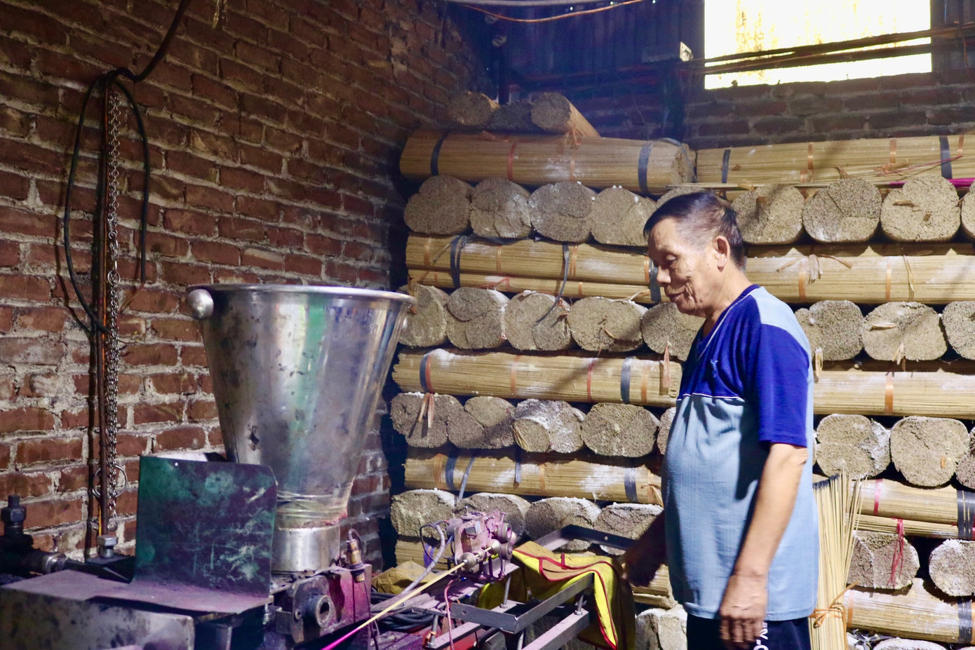 Ông Bình chỉ cách vận hành máy se hương tự động do mình tự chế tạo. Ảnh: Lâm Thùy Dương.