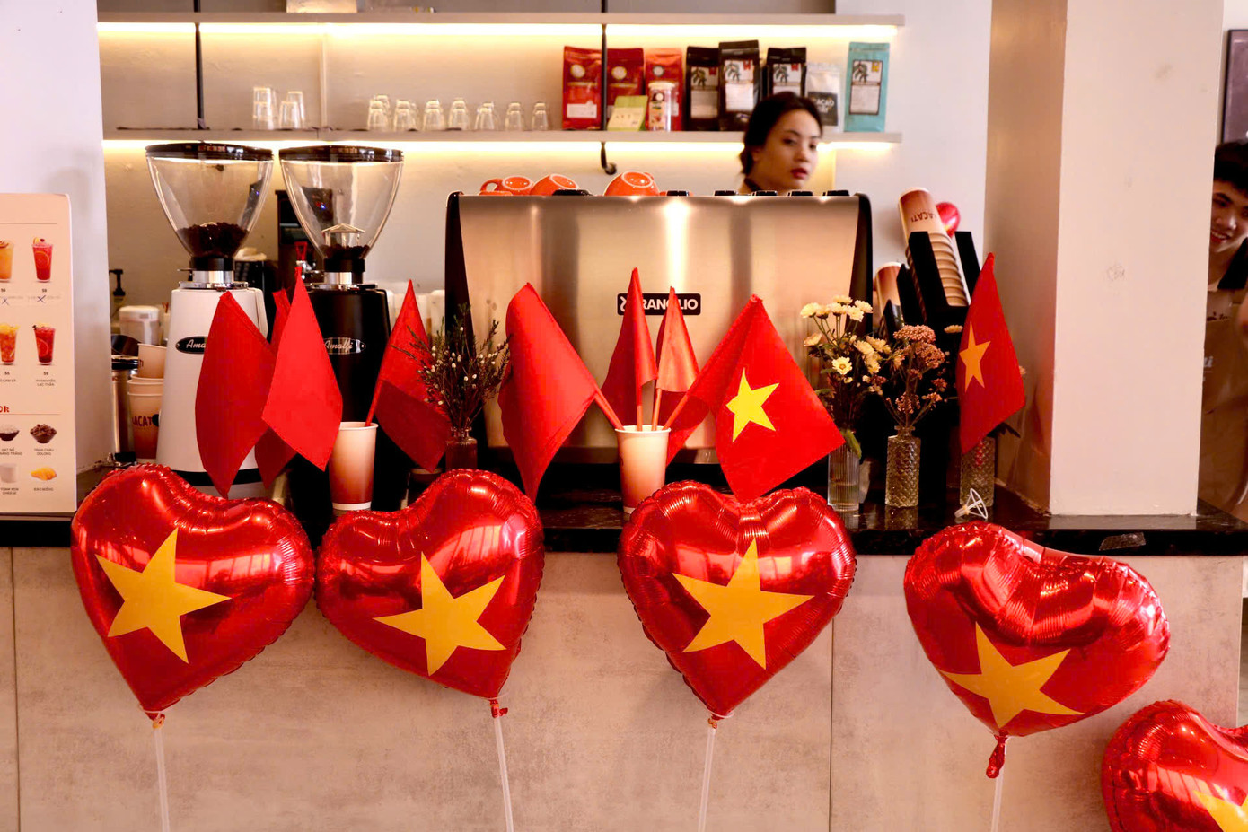 Tại quán cà phê trên đường Nguyễn Đình Thi, không gian được trang trí rực rỡ với cờ Tổ quốc và bóng hình trái tim màu đỏ có gắn sao vàng ở giữa, mang đậm tinh thần yêu nước, hướng tới kỷ niệm 30/4.
