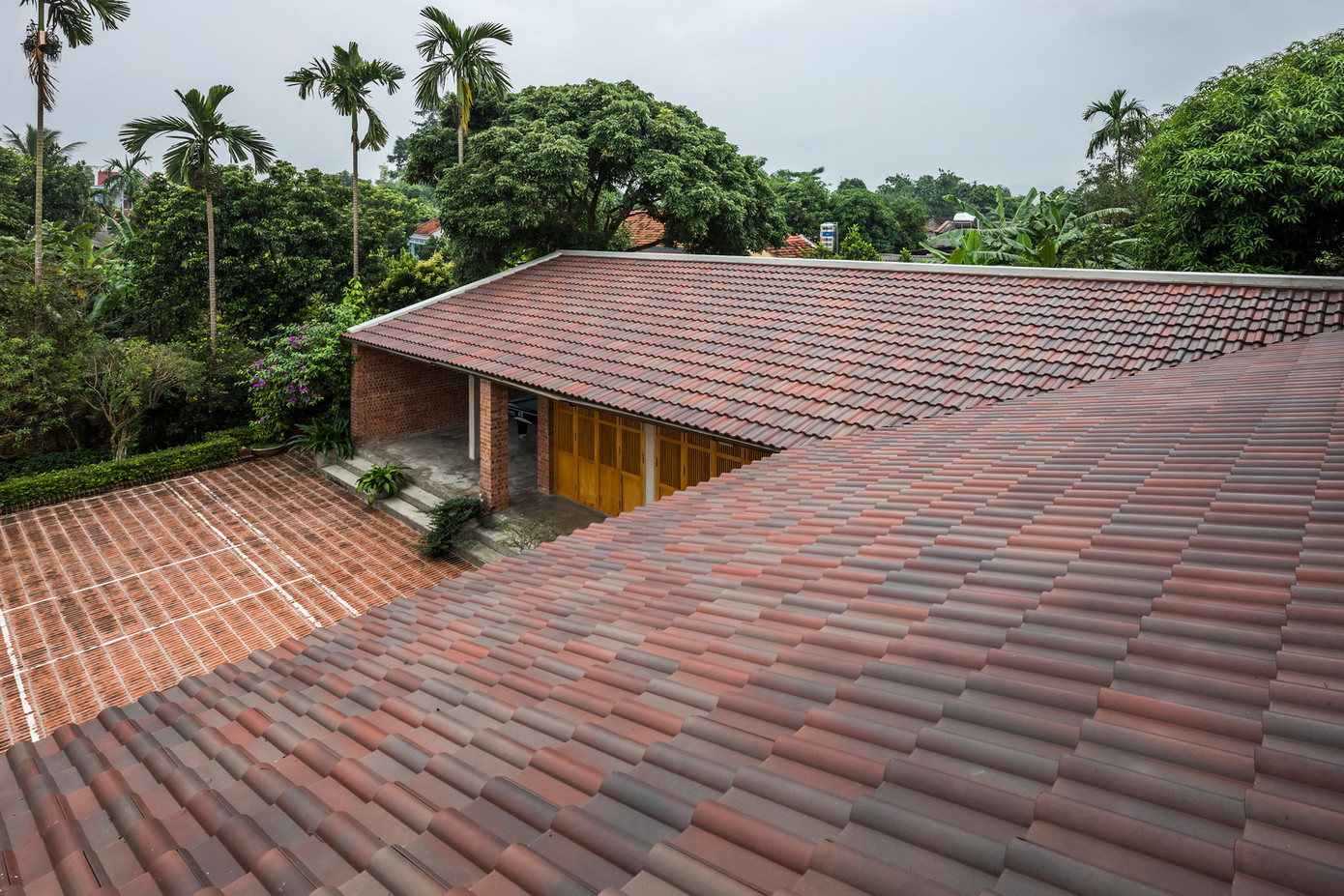 Tường và sân đều sử dụng gạch đỏ không trát, mang lại cảm giác ấm cúng cho cảnh quan.