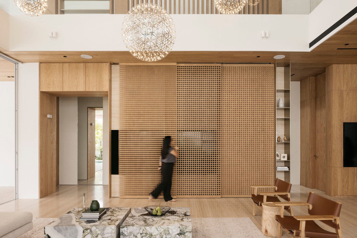 Các tấm chắn bằng gỗ thủ công lớn có thể trượt sang hai bên để lộ màn hình tivi, giúp giấu gọn thiết bị khi không sử dụng.