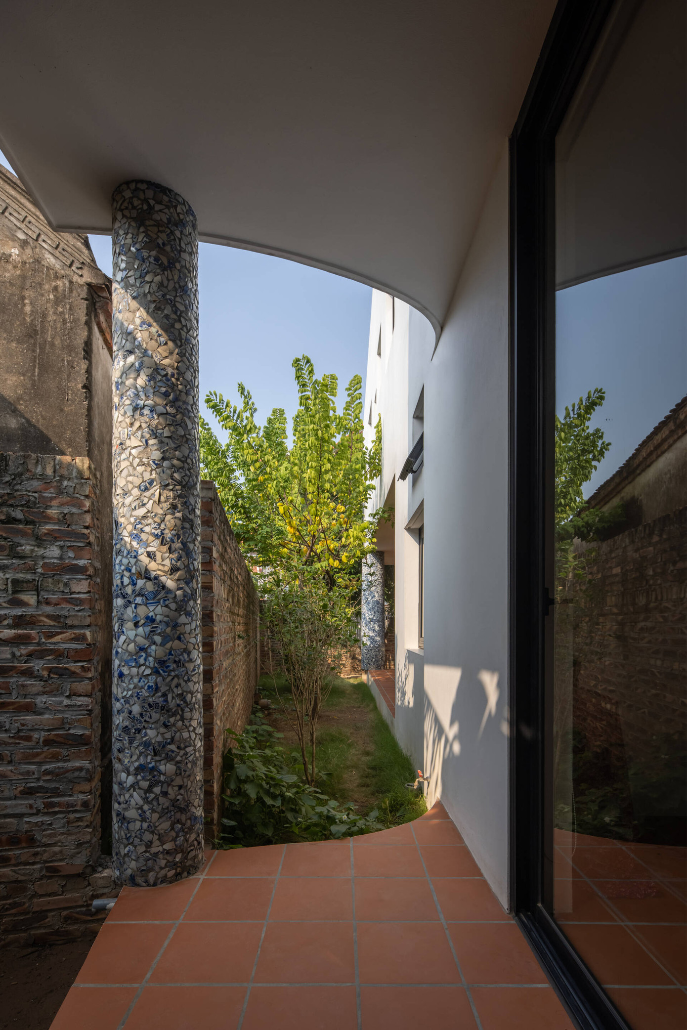 Một điều thú vị ở ngôi nhà là việc sử dụng những mảnh gốm nhỏ từ bát đĩa, chai lọ men lam truyền thống để ốp lên hai cột tròn ở hiên nhà. Đây không chỉ là một giải pháp tiết kiệm mà còn là một cách sáng tạo để lưu giữ và tái hiện những giá trị văn hóa xưa.