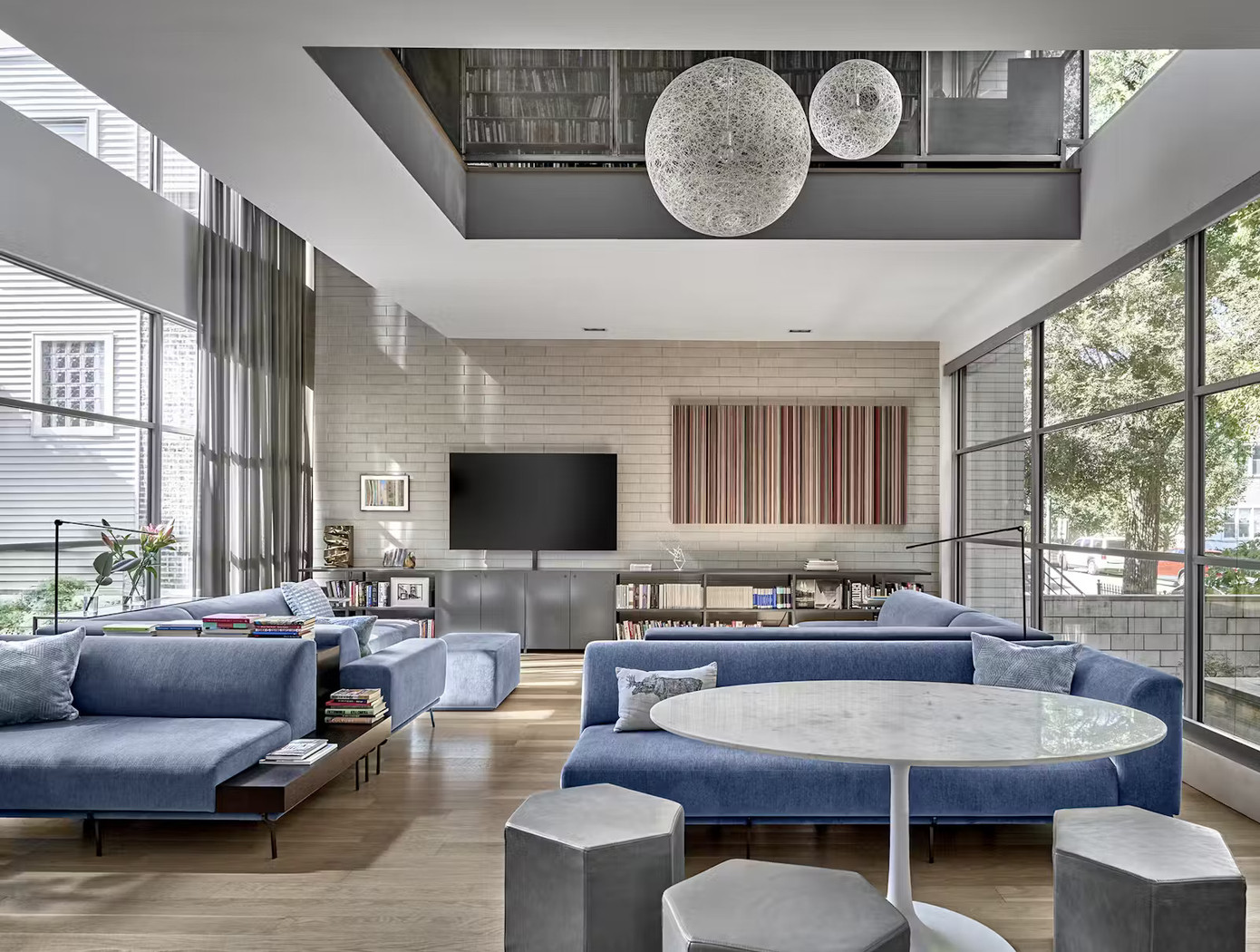 Phòng khách phía trước được ánh sáng tự nhiên chiếu từ hai chiều nhờ các khung cửa sổ lớn hướng Nam và Bắc, giúp không gian luôn tràn ngập ánh sáng ngay cả ngày đồng thời mở rộng tầm nhìn ra sân trong.