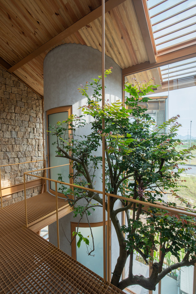 Một bức tường cây xanh kéo dài từ tầng trệt lên mái nhà không chỉ làm đẹp mà còn lọc không khí tự nhiên. Phần mái có thể mở linh hoạt, cho phép ánh sáng và gió tự nhiên len lỏi vào từng góc nhà.