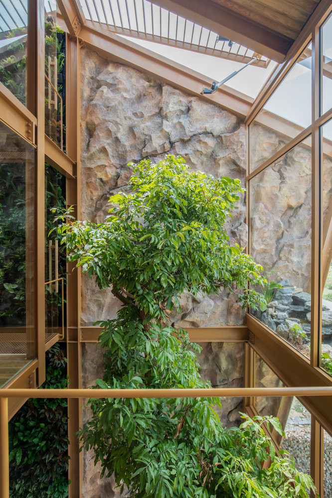Một bức tường cây xanh kéo dài từ tầng trệt lên mái nhà không chỉ làm đẹp mà còn lọc không khí tự nhiên. Phần mái có thể mở linh hoạt, cho phép ánh sáng và gió tự nhiên len lỏi vào từng góc nhà.