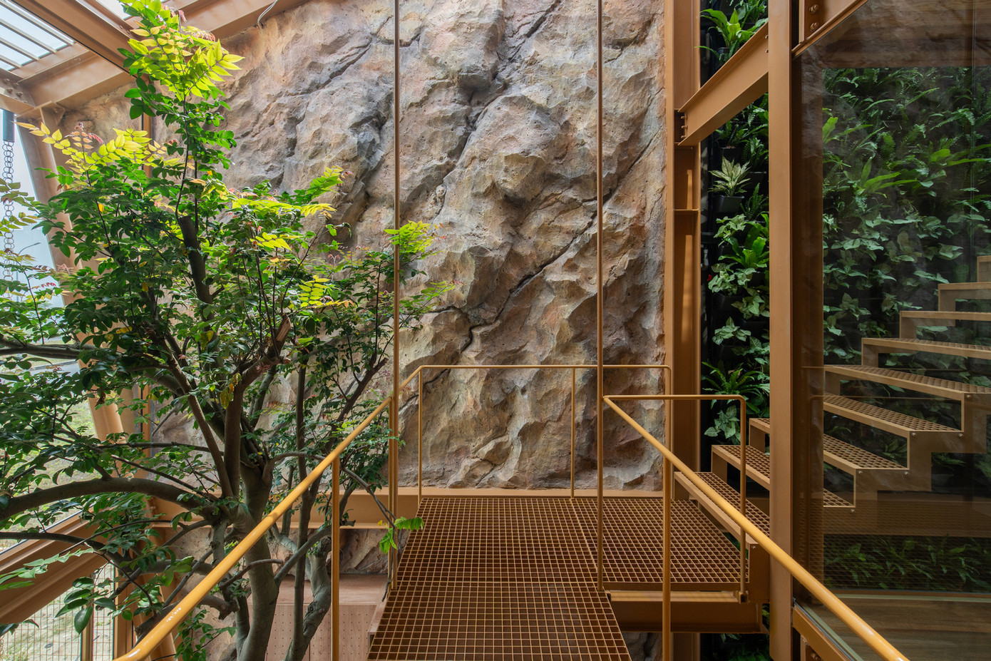 Một bức tường cây xanh kéo dài từ tầng trệt lên mái nhà không chỉ làm đẹp mà còn lọc không khí tự nhiên. Phần mái có thể mở linh hoạt, cho phép ánh sáng và gió tự nhiên len lỏi vào từng góc nhà.