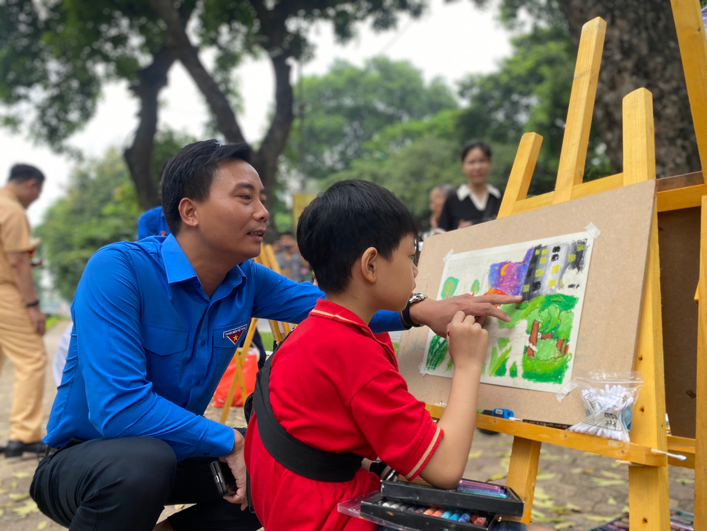 Anh Nguyễn Đức Tiến, Phó Bí thư Thường trực Thành Đoàn, Chủ tịch Hội LHTN TP Hà Nội động viên các em thiếu nhi vẽ tranh về an toàn giao thông. Ảnh: Bảo Anh