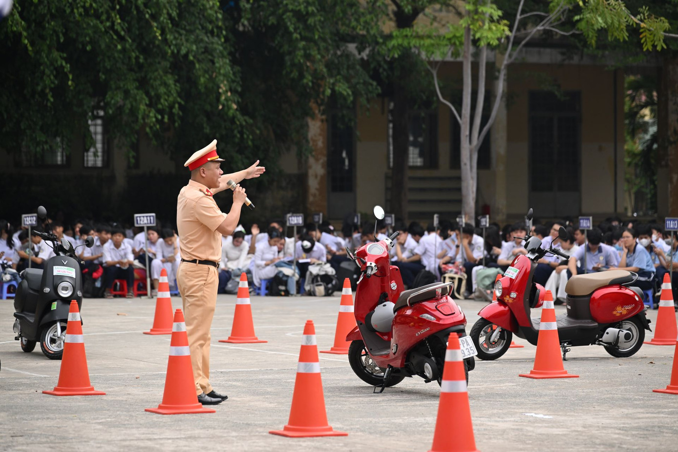 Các em học sinh lắng nghe những chia sẻ về giao thông an toàn từ cảnh sát giao thông.