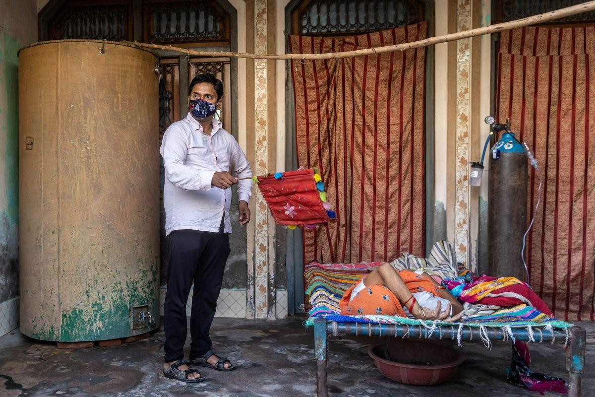 Dinesh Kumar, 32 tuổi đứng quạt cho mẹ khi bà này bị khó thở. Ảnh: Reuters