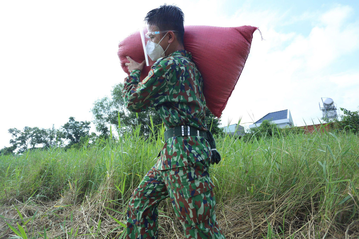 Các chiến sĩ trẻ năng nổ vác từng bao lúa của người dân từ ngoài đồng về tận nhà.
