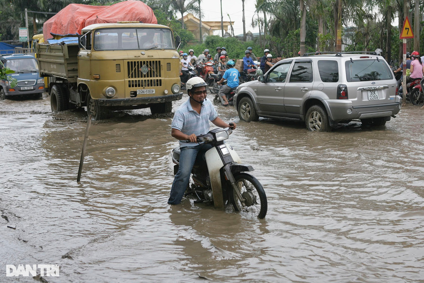 "Con đường đau khổ" là cái tên được người dân đặt cho QL32 thuộc địa phận Hà Tây cũ. Là quốc lộ song đường nhỏ, mật độ giao thông cao khiến mặt đường hỏng nặng, ổ gà, ổ voi dày đặc, bụi mù mịt. Ảnh chụp QL32 tại đoạn qua chợ đầu mối Minh Khai (huyện Từ Liêm cũ) sau cơn mưa lớn năm 2008.