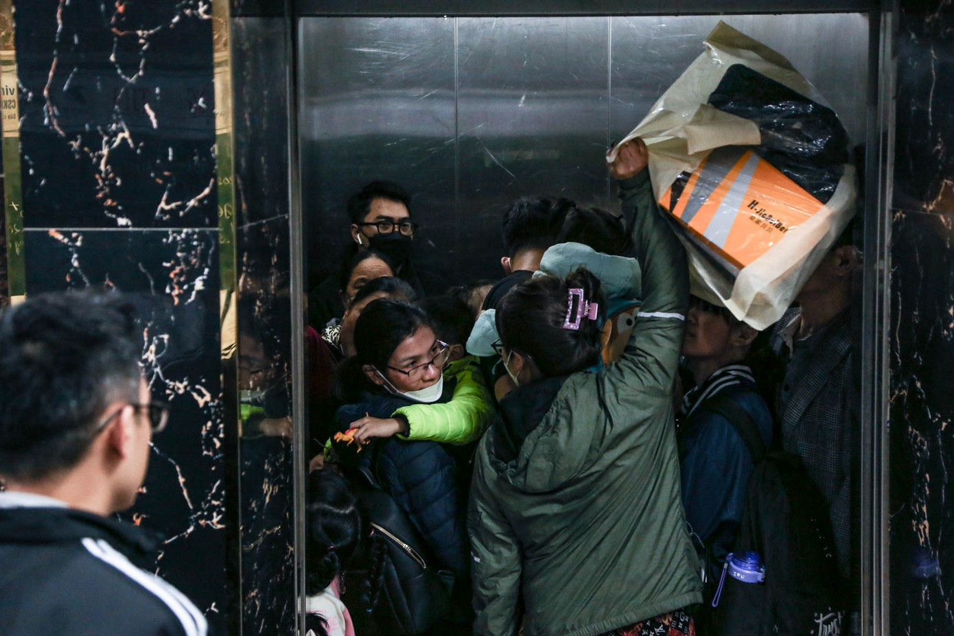 Nhiều người phải chen lấn để có lượt vào thang máy sớm nhất. Đợi được 5 phút, chị Hoàng Thị Mai, ở tầng 4 quyết định bỏ cuộc và đi thang bộ. “Tôi sợ quá lâu và không đến lượt được vào do quá tải nên đi bộ cho nhanh”, chị Mai nói.