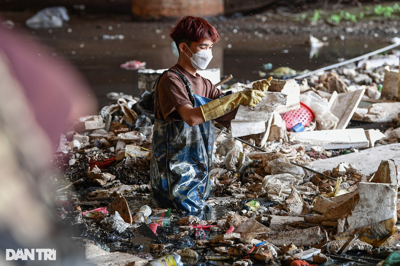 Sâu trong lòng kênh La Khê, mực nước ngập ngang bụng, các tình nguyện viên di chuyển khó khăn, dùng cào để thu gom rác thải.