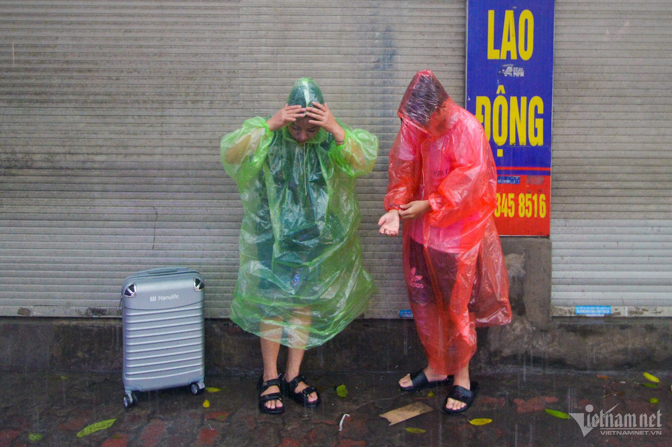 Chị Phạm Hải Yến cùng con trai đang trên đường về Thanh Hóa gặp mưa nên phải trú tạm dưới mái hiên một cửa hàng chưa mở. “Tôi đặt xe từ trước đó một tuần mà vẫn không có, bây giờ đành đi nhờ xe người quen. Đi trên đường mưa gió đúng thật là vất vả”, chị nói.