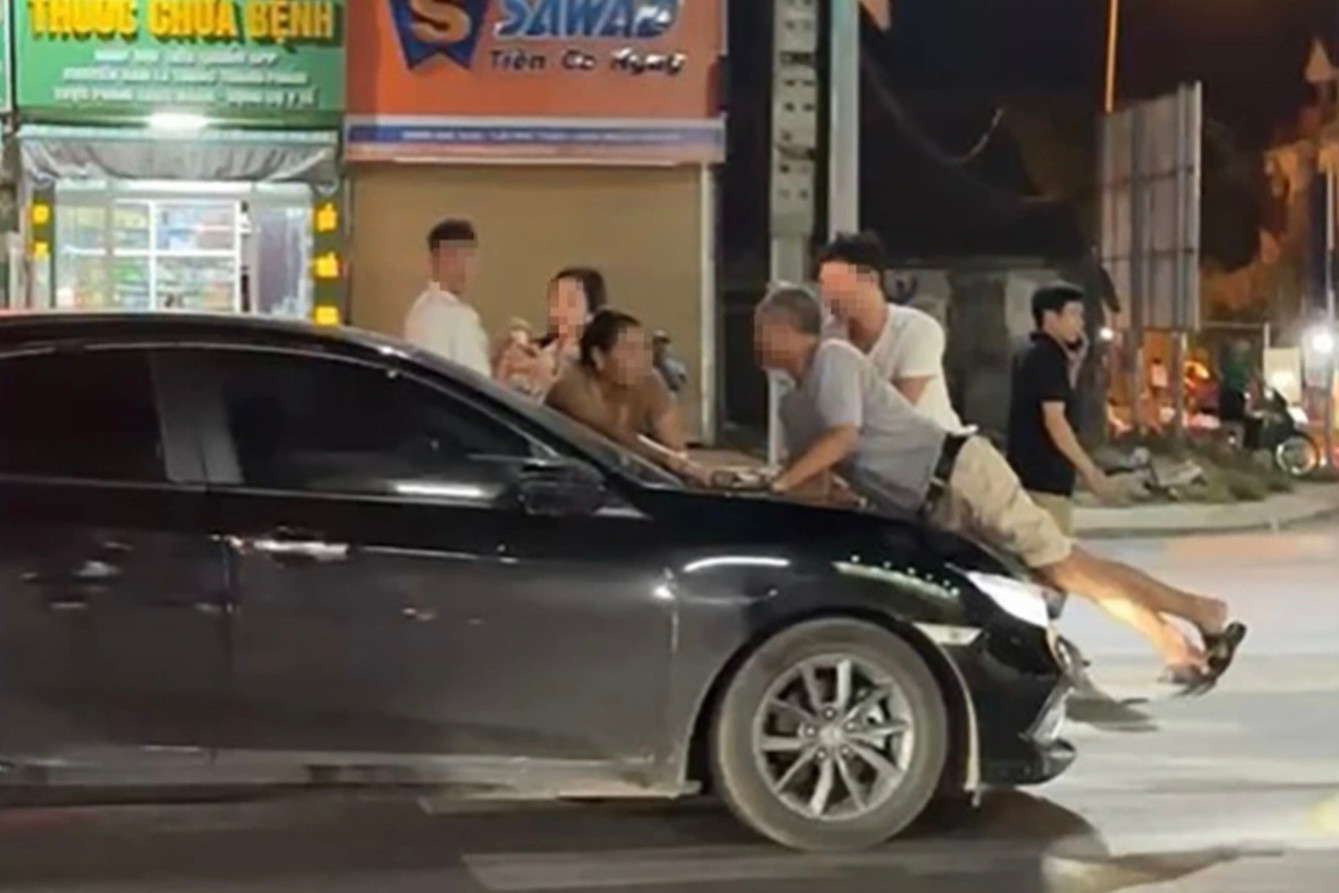 Người đàn ông lớn tuổi được cho là bố chồng chị B. bị hất lên nắp capo, chiếc xe sau đó vẫn tiếp tục di chuyển với tốc độ khá cao (ảnh chụp màn hình). Người đàn ông lớn tuổi được cho là bố chồng chị B. bị hất lên nắp capo, chiếc xe sau đó vẫn tiếp tục di chuyển với tốc độ khá cao (ảnh chụp màn hình).