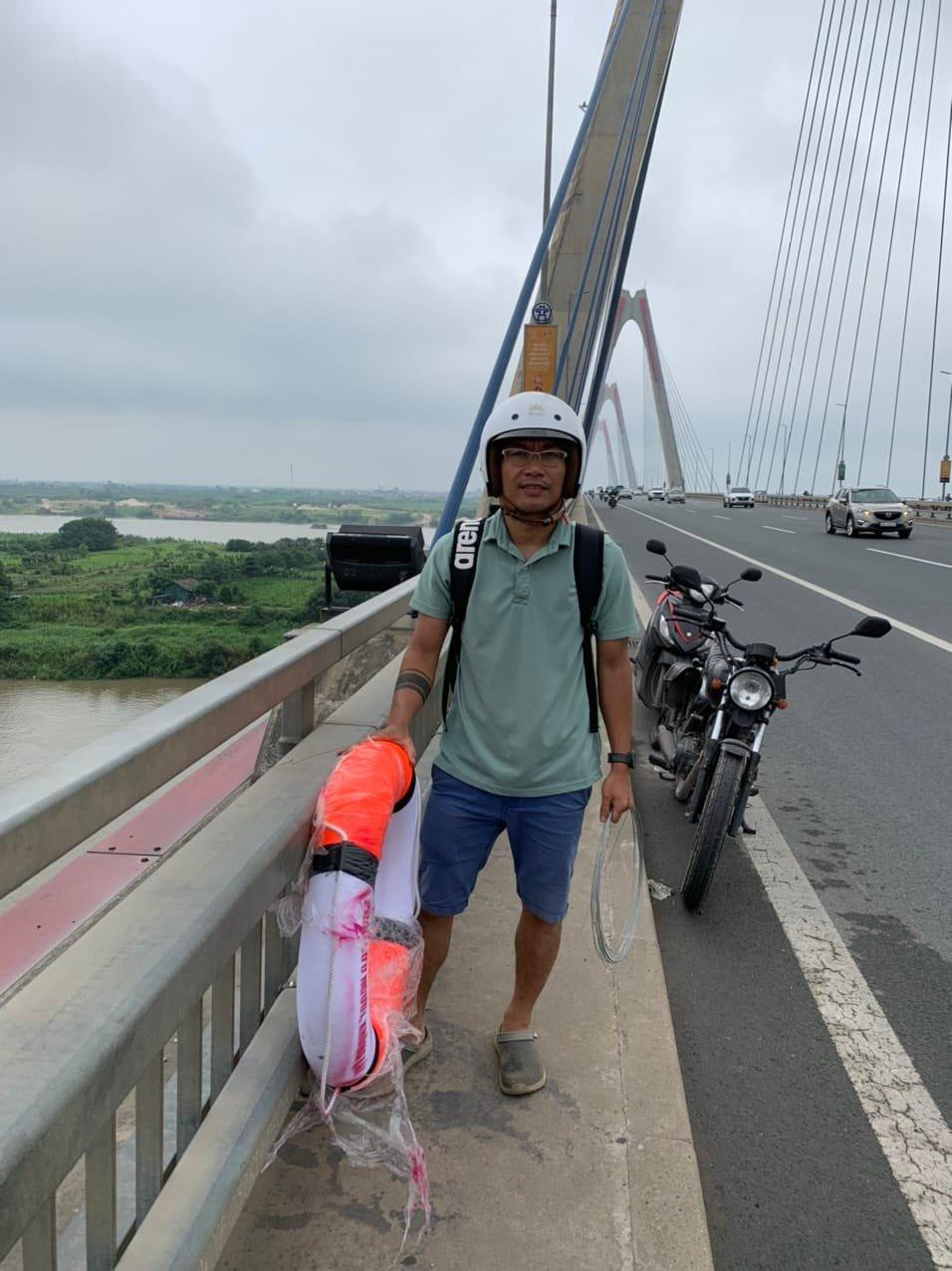 Một thành viên của nhóm lắp đặt phao cứu sinh trên cầu Nhật Tân. Ảnh nhân vật cung cấp.