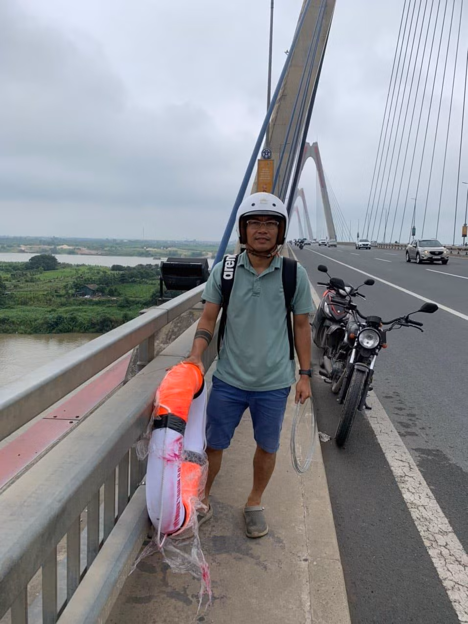 Một thành viên của nhóm lắp đặt phao cứu sinh trên cầu Nhật Tân. Ảnh nhân vật cung cấp.