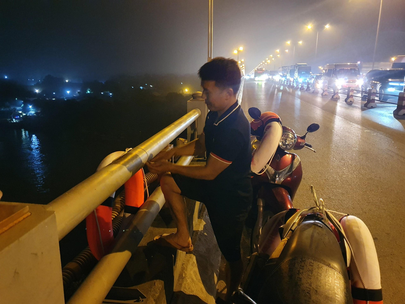 Một thành viên của nhóm thiện nguyện lắp đặt phao cứu sinh trên cầu Thanh Trì. Ảnh: Nhân vật cung cấp.