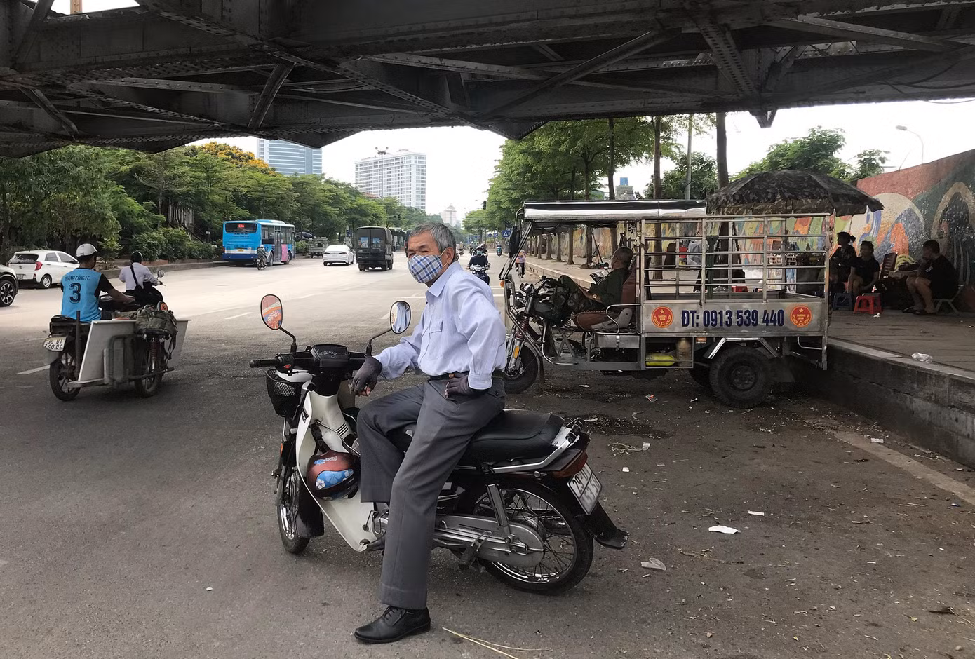 Dù trời trưa nắng gắt, đường ít người qua lại, nhưng ông Nguyễn Văn Hải (57 tuổi) vẫn đứng đón khách ở gầm cầu Long Biên, mong kiếm thêm thu nhập. Ảnh: Viết Hà