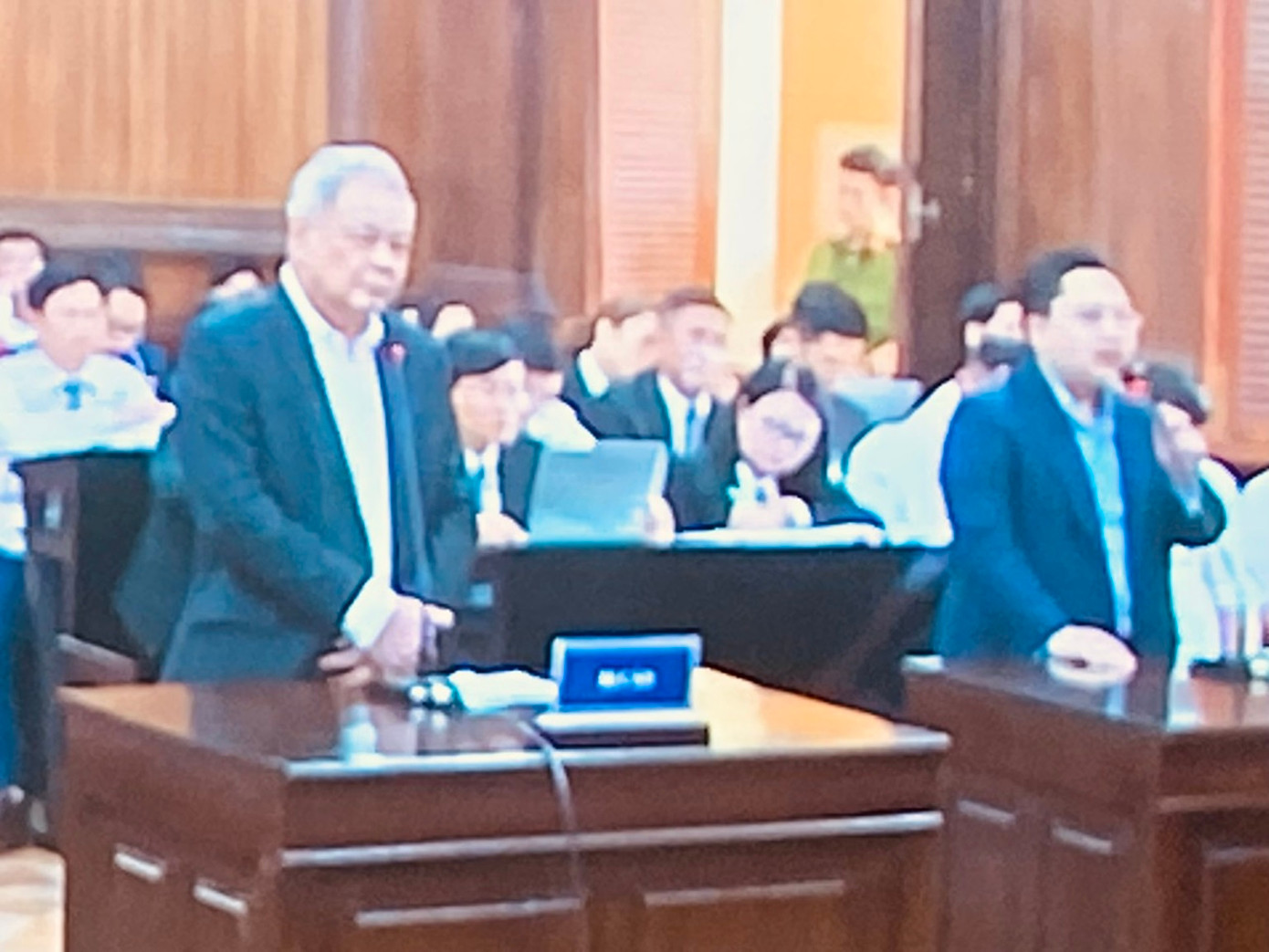 Ông Thanh (trái) và ông Phú (phải) đang đối chất tại tòa. Ảnh chụp qua màn hình.