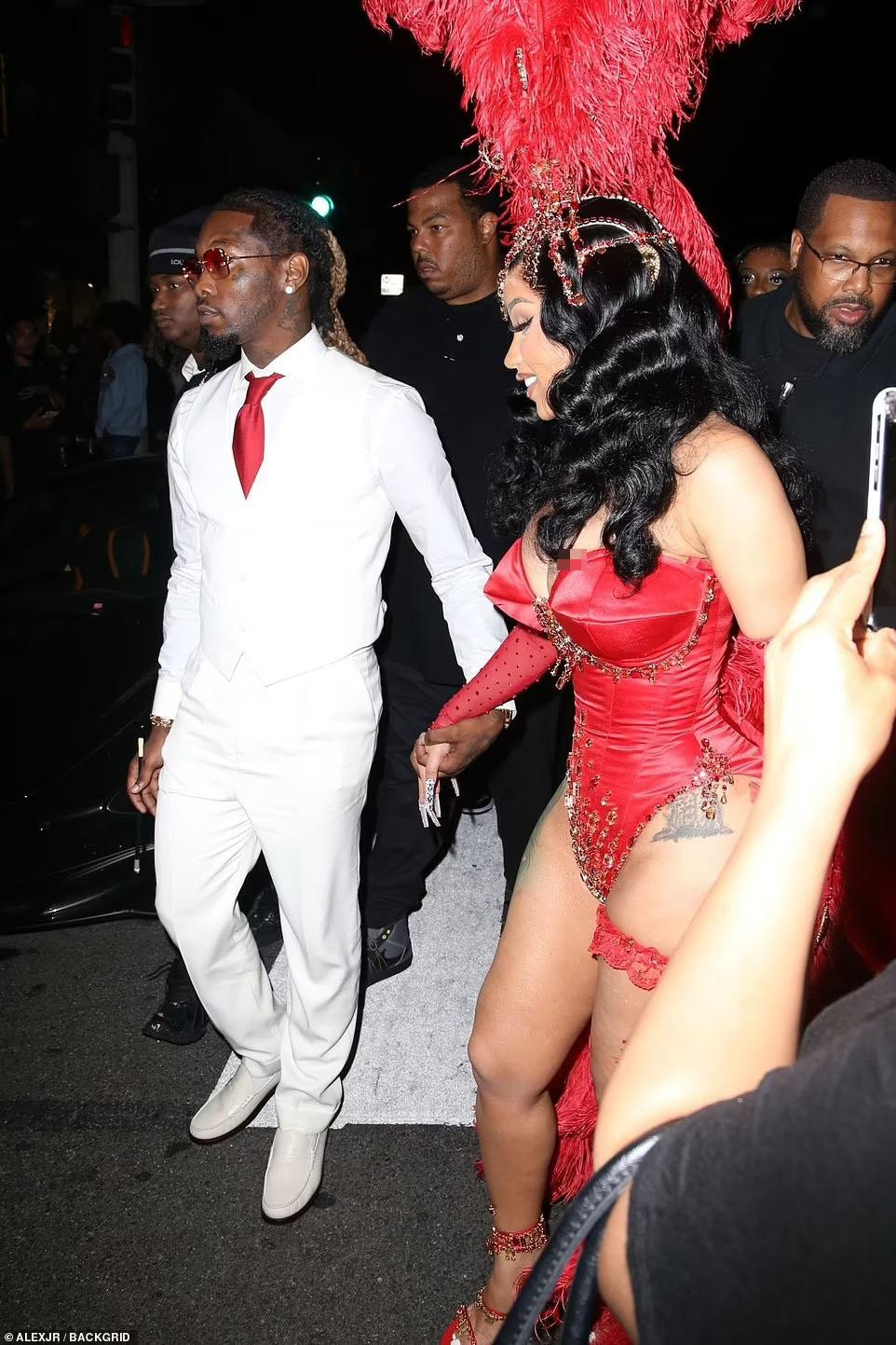 Nữ rapper nổi bật trong đêm với bộ bodysuit gắn lông vũ đỏ rực tôn đường cong "bốc lửa", kết hợp mũ đội đầu phong cách lễ hội Carnival và vô số vòng, chuỗi hạt lấp lánh. Tuy nhiên, phần cúp ngực nhỏ hơn so với vòng một khiến người đẹp 9X gặp sự cố hớ hênh. Trong khi đó, Offset diện lễ phục trắng phối với cà vạt đỏ bảnh bao. Ảnh: Back Grid.